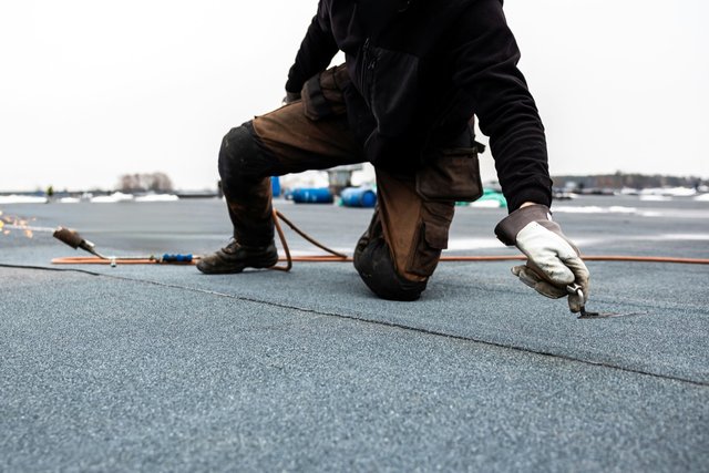 Handwerker bei der fachgerechten Flachdachabdichtung